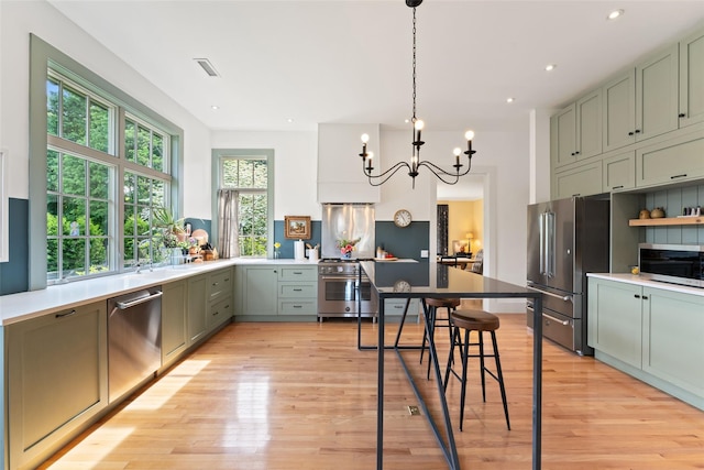 kitchen with high quality appliances, a chandelier, light wood-style flooring, decorative light fixtures, and recessed lighting