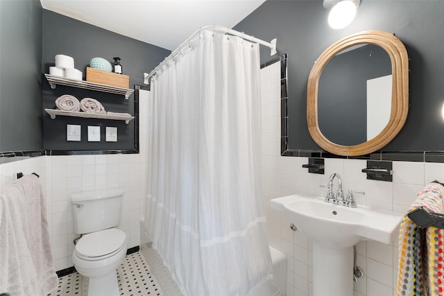 full bath featuring tile walls, a shower with curtain, toilet, and a wainscoted wall