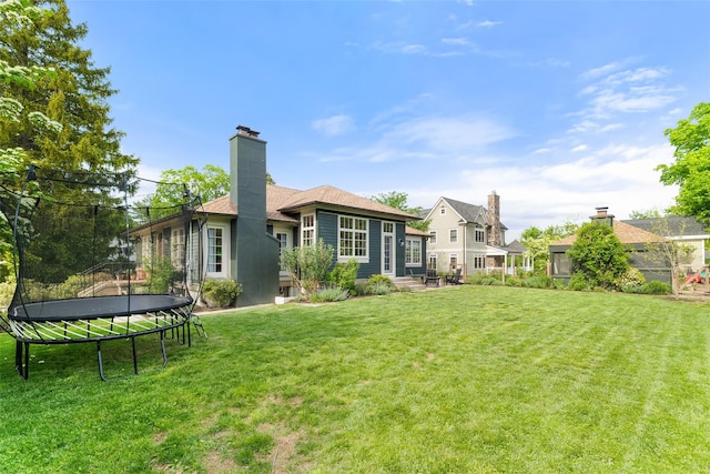 back of property with a trampoline, a lawn, and a chimney