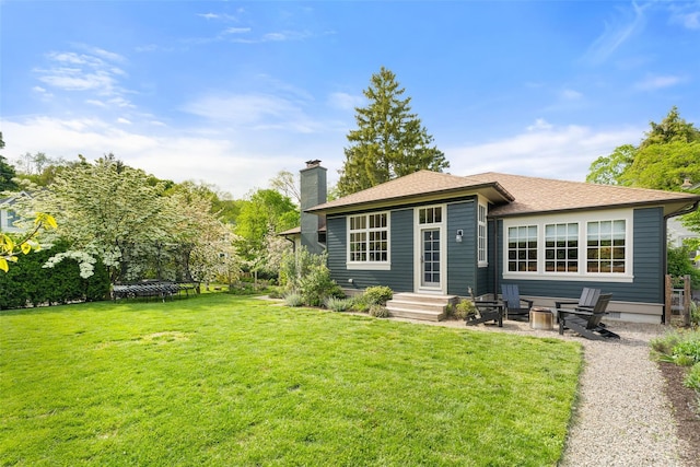 back of house featuring a trampoline, a chimney, a yard, and a patio area