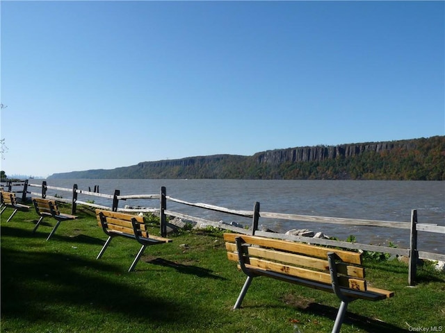 view of community with a water and mountain view, a lawn, and a wooded view