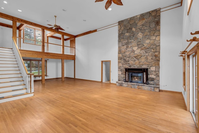 unfurnished living room featuring plenty of natural light, a ceiling fan, light wood finished floors, and a high ceiling