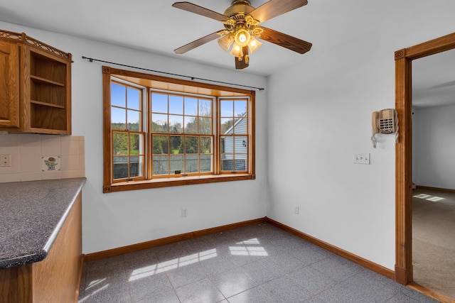unfurnished dining area featuring a ceiling fan and baseboards