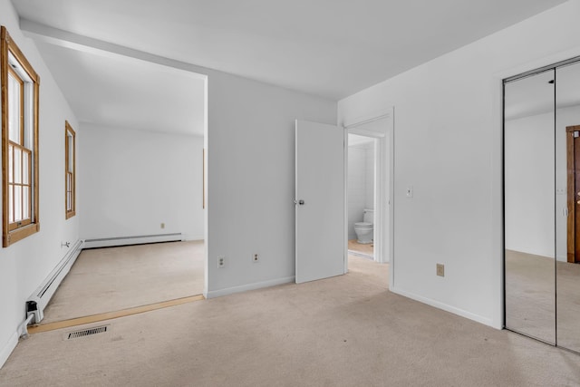 unfurnished bedroom featuring visible vents, a closet, baseboards, baseboard heating, and carpet