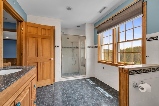 full bathroom with vanity, a stall shower, and visible vents