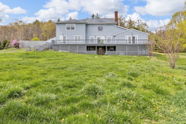 back of property with a lawn, a wooden deck, and a chimney