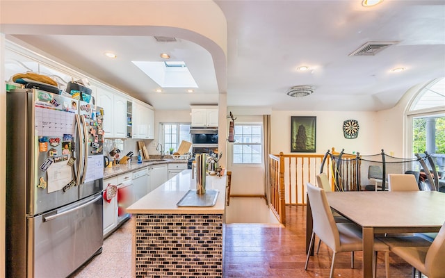 kitchen featuring a sink, white cabinets, freestanding refrigerator, and visible vents
