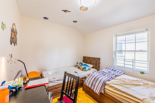 bedroom with vaulted ceiling and wood finished floors