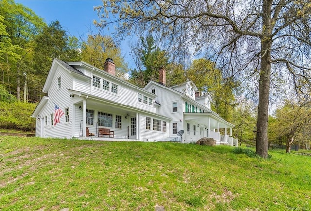back of property with a lawn, a chimney, and a patio