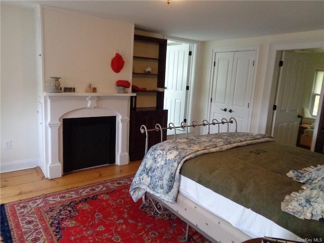 bedroom featuring a closet, wood finished floors, and a fireplace