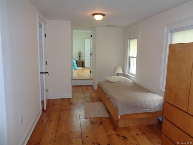 bedroom with baseboards, light wood-style flooring, and visible vents