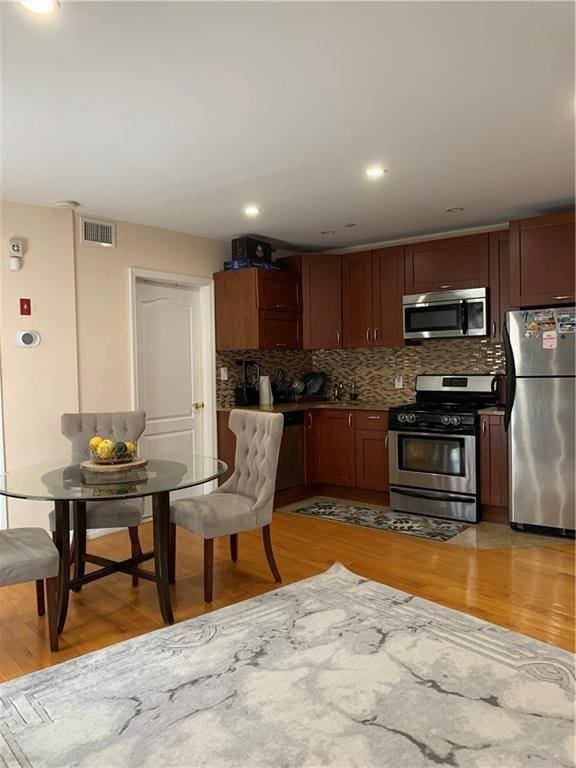 kitchen featuring visible vents, light wood-style floors, tasteful backsplash, and stainless steel appliances