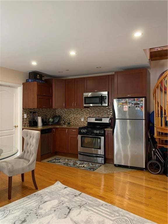 kitchen with light wood-type flooring, decorative backsplash, appliances with stainless steel finishes, and recessed lighting