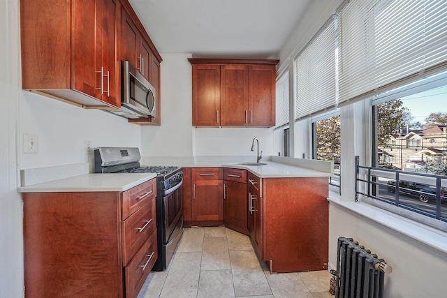 1754 Seward Ave, Bronx, NY 10473 - kitchen featuring a peninsula, radiator heating unit, light countertops, a sink, and appliances with stainless steel finishes