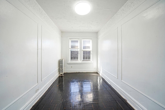 1754 Seward Ave, Bronx, NY 10473 - unfurnished room with wood finished floors, a textured ceiling, a decorative wall, and radiator heating unit