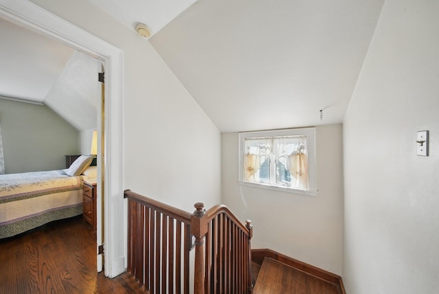 corridor featuring baseboards, vaulted ceiling, dark wood-style flooring, and an upstairs landing