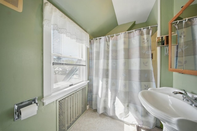 full bathroom featuring a shower with shower curtain, vaulted ceiling, a sink, and visible vents