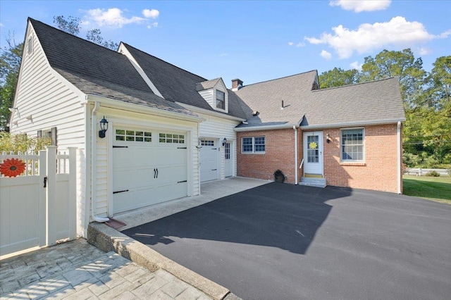 82 E Cedar St, Poughkeepsie, NY 12601 - cape cod home featuring asphalt driveway, brick siding, a chimney, an attached garage, and roof with shingles
