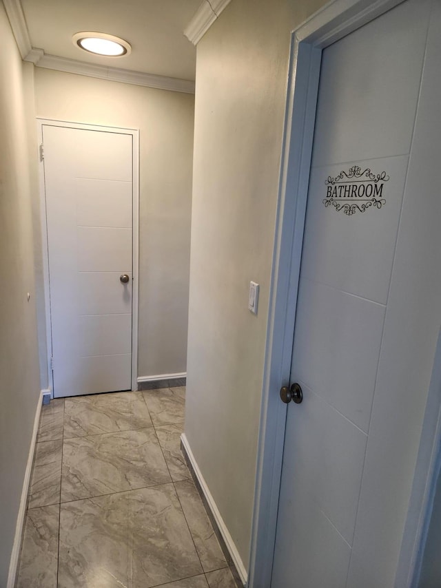 hallway with crown molding, baseboards, and marble finish floor