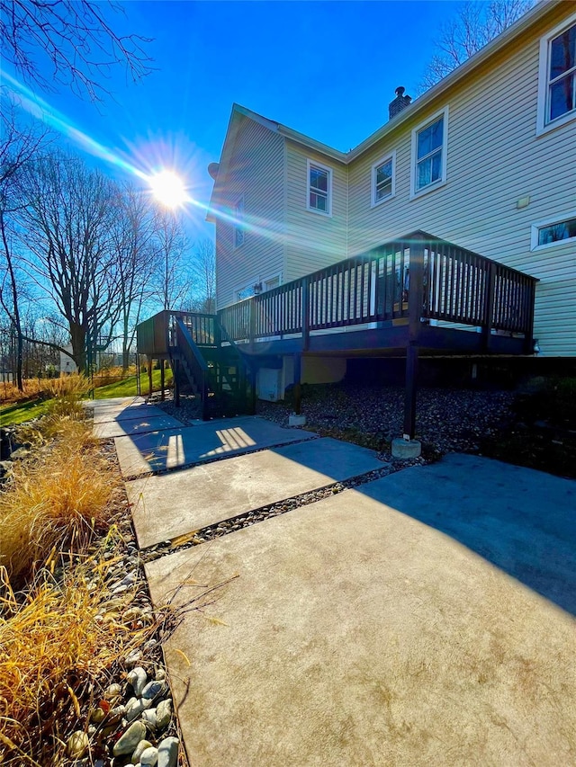 back of property featuring a patio area, a wooden deck, and a chimney