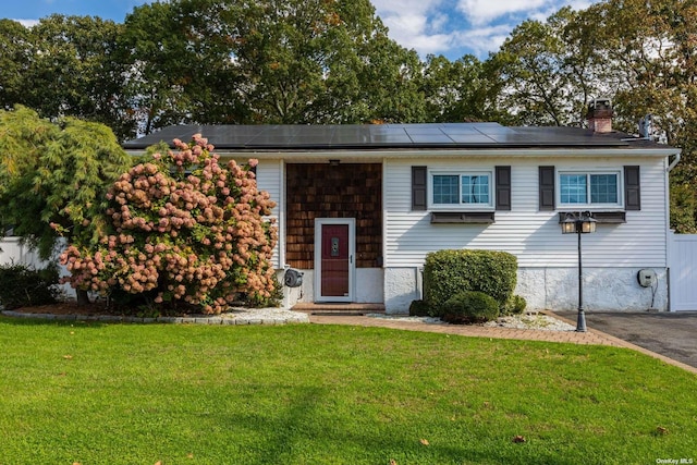 split foyer home featuring solar panels, a front yard, and a chimney