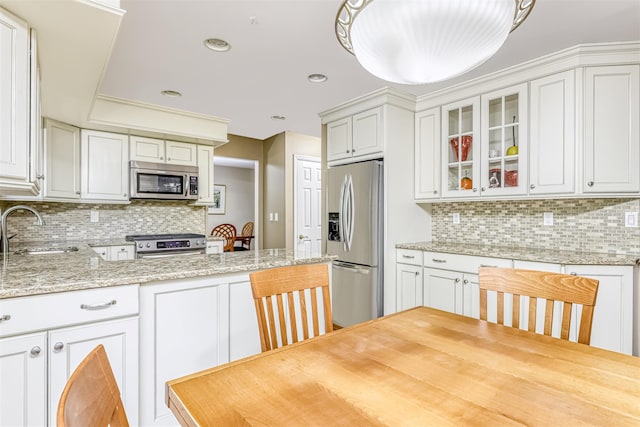 8 Ferndale Rd, New City, NY 10956 - kitchen featuring appliances with stainless steel finishes, a sink, decorative backsplash, glass insert cabinets, and light stone countertops