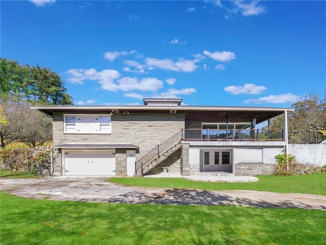 back of house featuring a lawn, stairs, stone siding, and a garage
