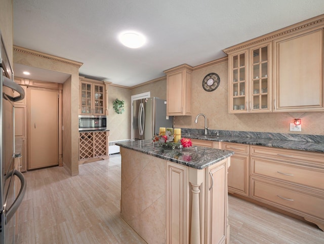 kitchen with glass insert cabinets, appliances with stainless steel finishes, a kitchen island, and light wood-style flooring