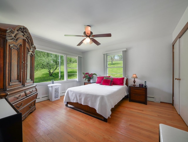 bedroom featuring ceiling fan, baseboard heating, and light wood-style floors