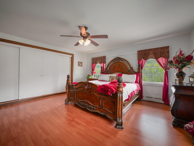 bedroom featuring a closet, ceiling fan, baseboard heating, and light wood-type flooring