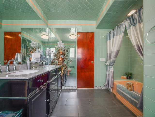 full bathroom featuring double vanity, a washtub, tile patterned floors, and a sink