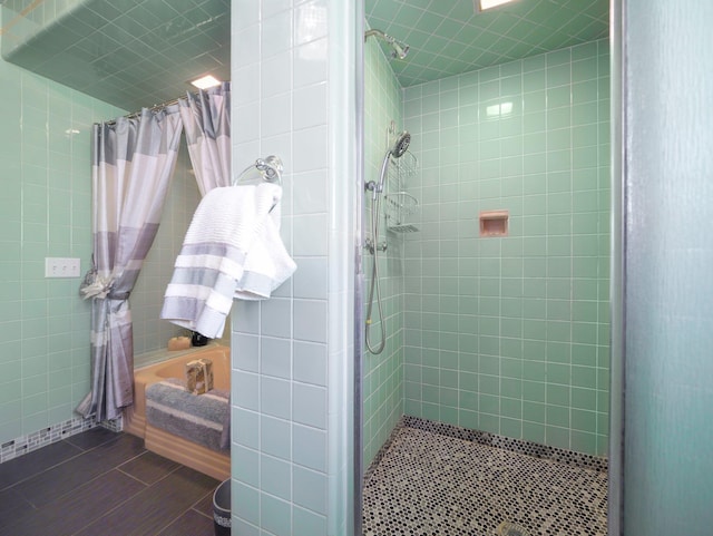 bathroom with tile walls, tile patterned flooring, and a tile shower