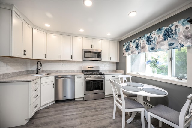 kitchen with a sink, white cabinetry, tasteful backsplash, and stainless steel appliances
