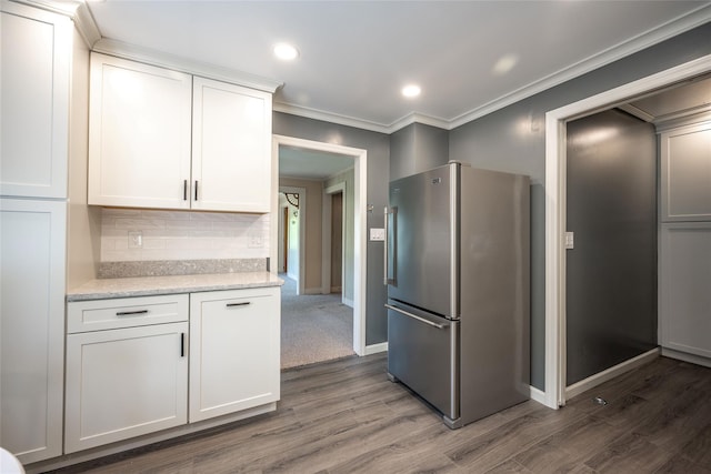 kitchen featuring decorative backsplash, dark wood finished floors, baseboards, freestanding refrigerator, and ornamental molding