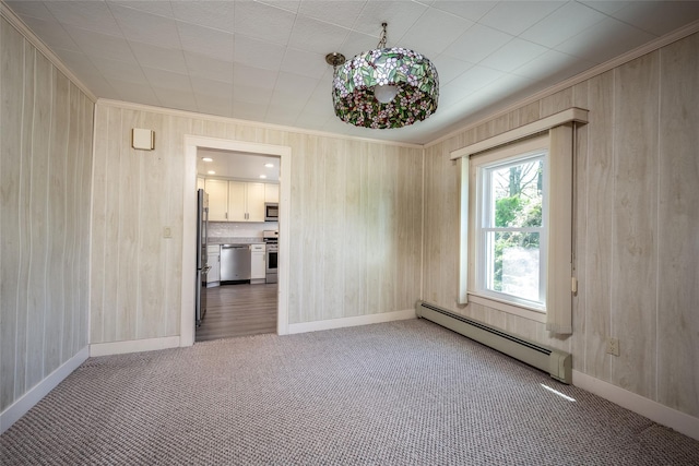 empty room featuring wooden walls, ornamental molding, carpet, and a baseboard radiator