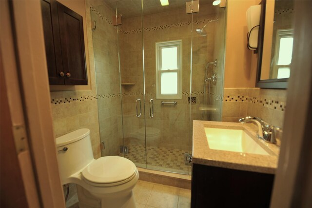 full bath featuring tile patterned flooring, a shower stall, toilet, and tile walls