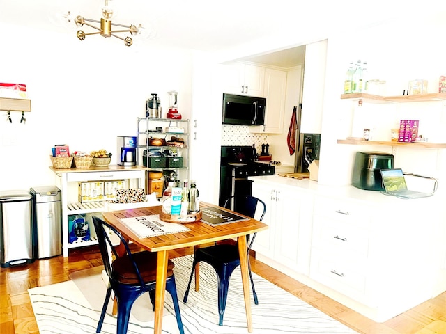 kitchen featuring black microwave, range with gas stovetop, light countertops, white cabinetry, and a chandelier