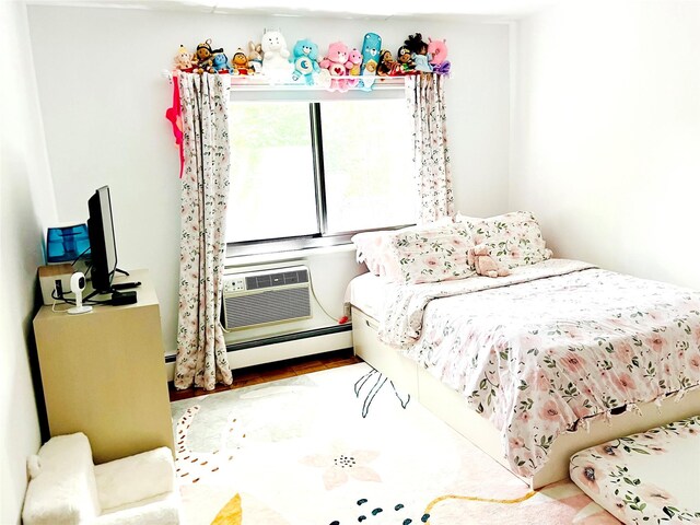 bedroom with baseboard heating and wood finished floors