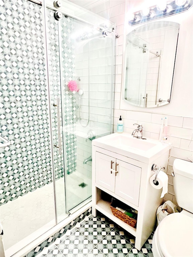 bathroom with toilet, a shower stall, tile walls, and vanity