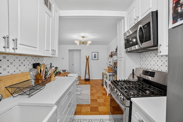 108 Sagamore Rd Unit 5F, Tuckahoe, NY 10707 - kitchen featuring appliances with stainless steel finishes, white cabinetry, light countertops, tasteful backsplash, and a chandelier