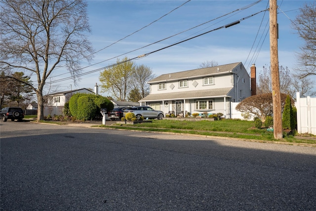 traditional-style home featuring fence and a chimney