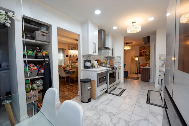 kitchen with tasteful backsplash, white cabinetry, light countertops, stainless steel appliances, and wall chimney exhaust hood