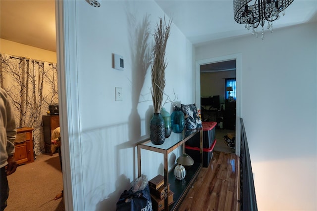 hallway with an inviting chandelier and wood finished floors