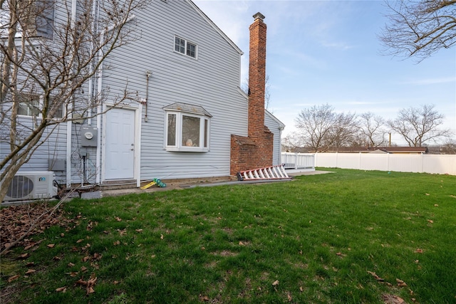 back of house featuring ac unit, fence, a yard, and a chimney