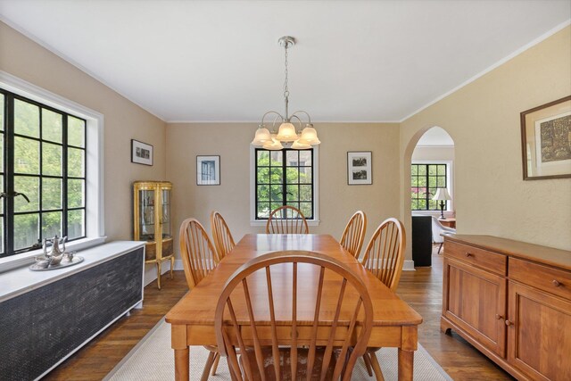 dining area with arched walkways, a chandelier, crown molding, and dark wood-type flooring