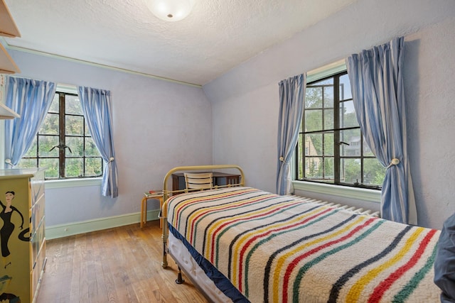 bedroom featuring baseboards, multiple windows, hardwood / wood-style floors, and a textured ceiling