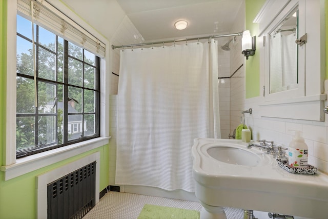 bathroom with radiator, tile patterned floors, shower / bath combination with curtain, and a sink