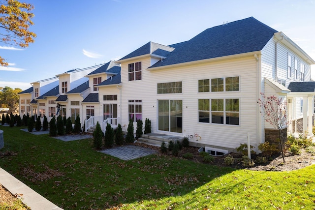 back of house with a shingled roof, a yard, and a residential view