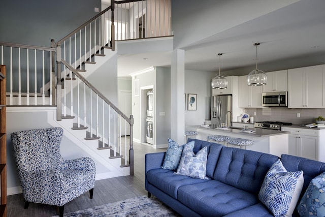 living area with baseboards, wood finished floors, stairway, and a towering ceiling