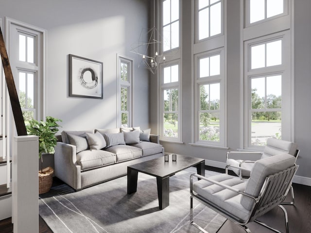living room with dark wood finished floors, a healthy amount of sunlight, and a towering ceiling